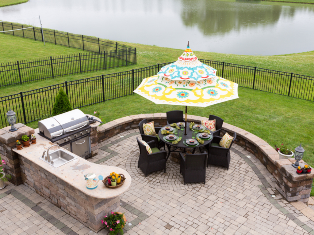 a-patio-with-a-grill-table-chairs-and-an-umbrella