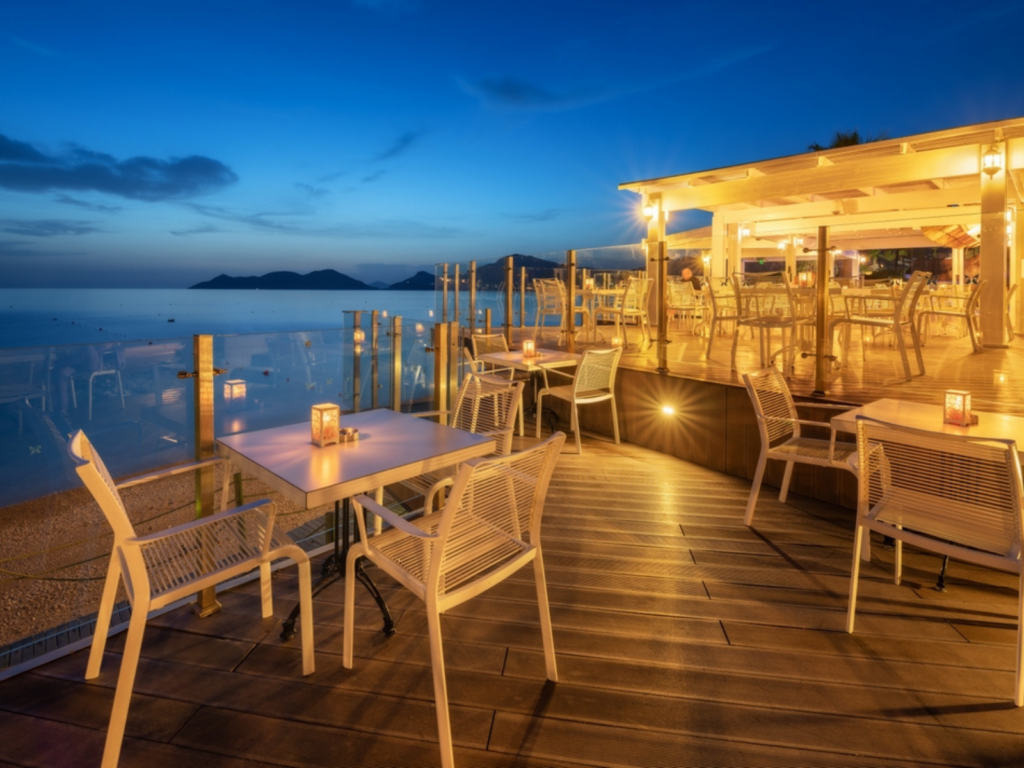 a-wooden-deck-with-tables-and-chairs-on-it