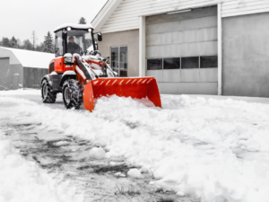 snowplow tractor clears path in front of building